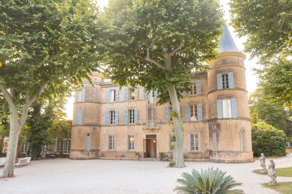 Façade du Château de Robernier baignée de lumière dorée, entourée de platanes centenaires en Provence, dans le Sud de la France.