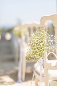 Détail d’un bouquet de gypsophile attaché à une chaise blanche pour la cérémonie extérieure au Château de Robernier.