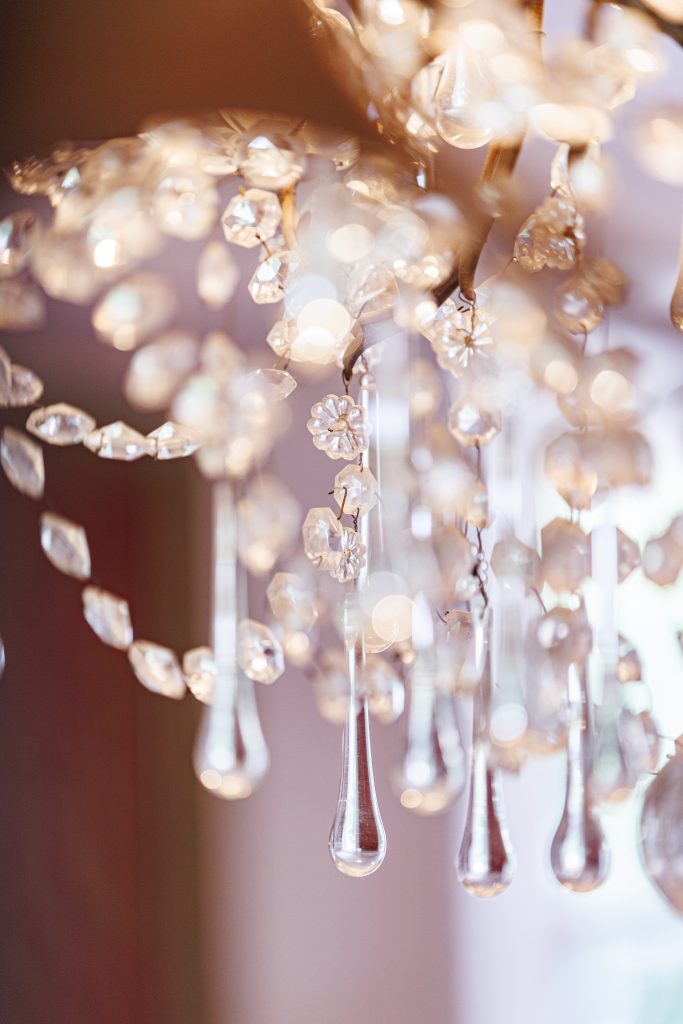 Détail flou artistique d’un lustre en cristal au Château de Robernier, photographié avec douceur par Studio JOLY Photographie.
