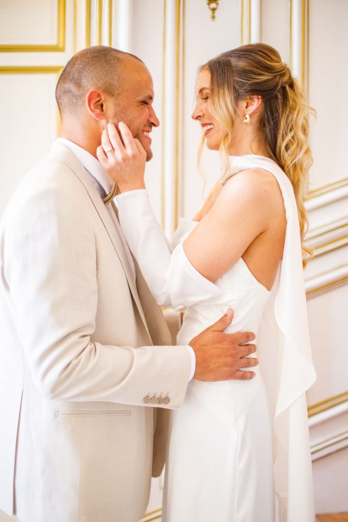 Mariés complices dans un salon élégant du Château de Robernier, capturés dans une lumière naturelle dorée par Studio JOLY Photographie.