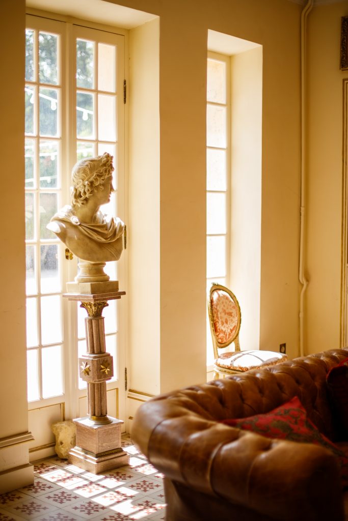 Intérieur élégant du Château de Robernier avec statue classique, lumière dorée et mobilier raffiné, capturé par Studio JOLY Photographie en Provence.
