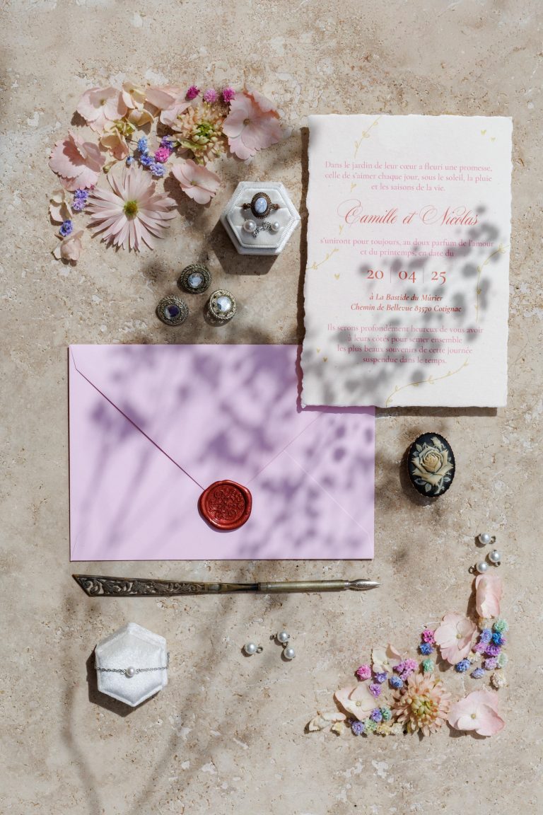Flatlay d’une papeterie de mariage élégante avec fleurs séchées, bijoux anciens et sceau de cire, photographié en lumière naturelle par Studio JOLY Photographie en Provence.