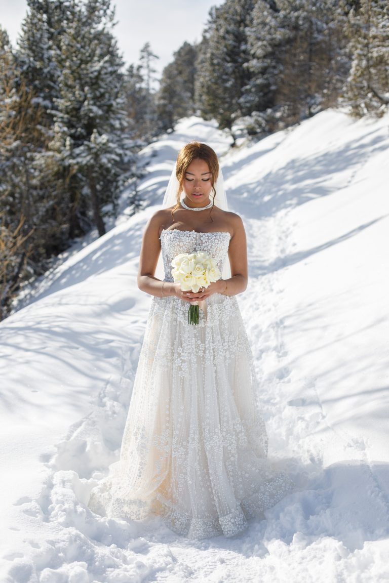 Mariée élégante en robe brodée de perles dans un paysage enneigé, photographiée lors d’un destination wedding d’hiver par Studio JOLY Photographie.