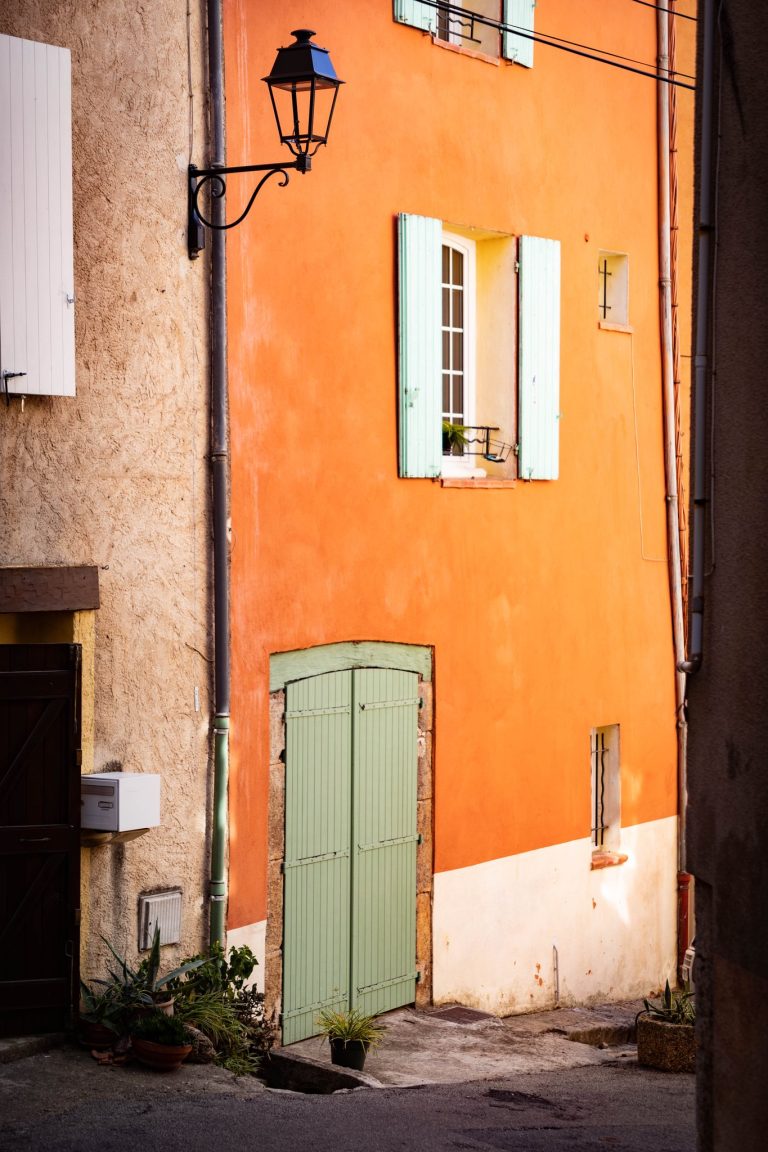 Façade orange et volets pastel dans une ruelle de Cotignac